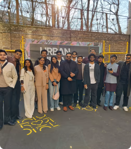 Group of 15 young adults outdoors in front of a graffiti wall