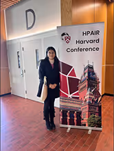 Woman beside a vertical banner for the HPAIR Harvard Conference