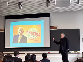 Man in a suit giving a presentation in a Harvard classroom