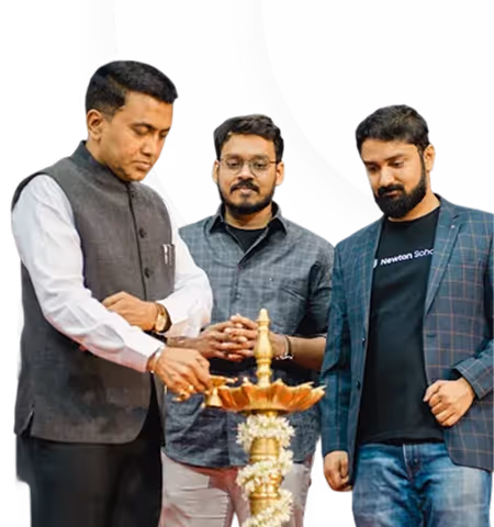 Three men standing together, with the man on the left lighting a traditional brass lamp.