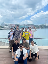Group of eight young men on a wooden deck with a cityscape backdrop